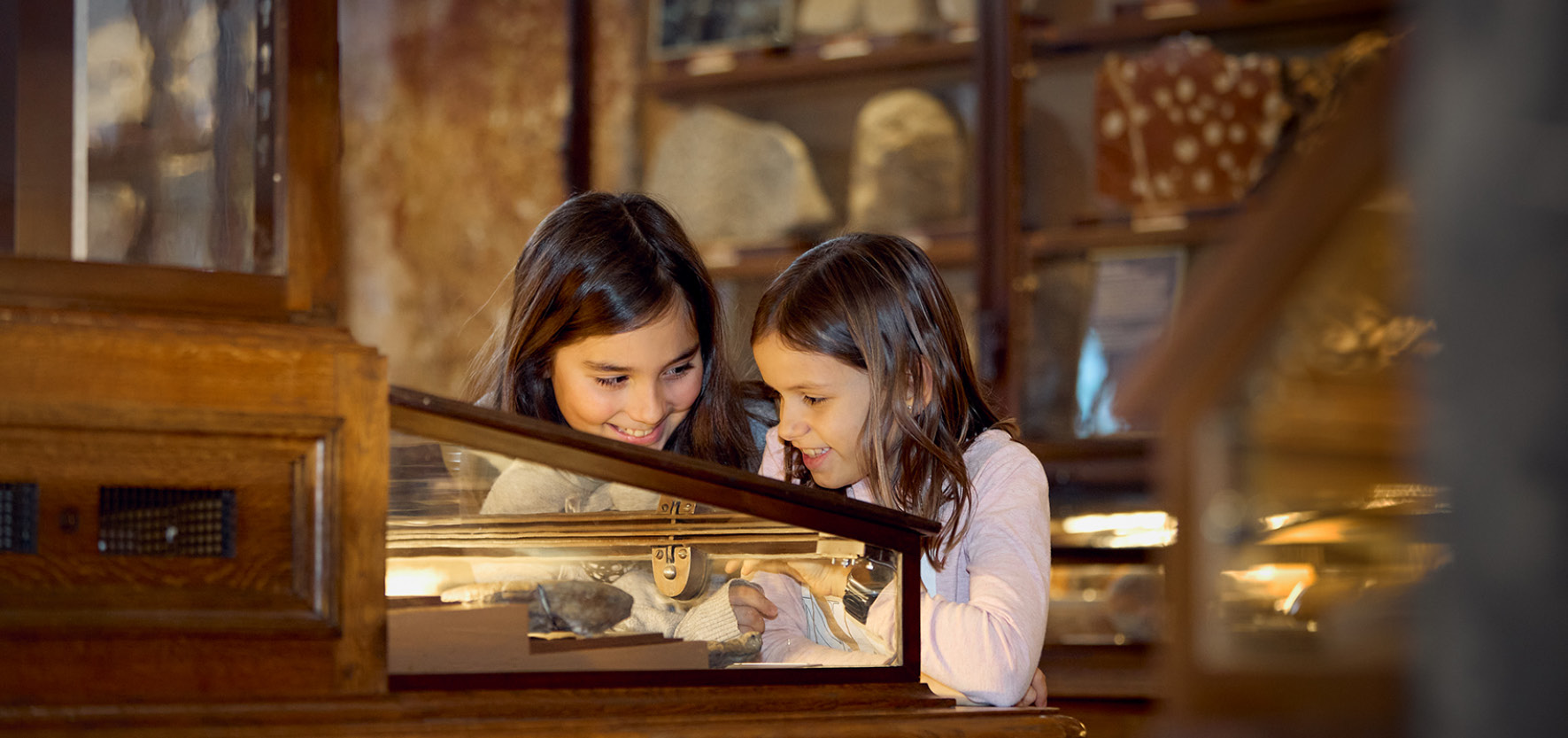 Kidsab6©Haeusler Zwei Kinder betrachten gemeinsam Exponate in einem Museumsvitrinenschrank